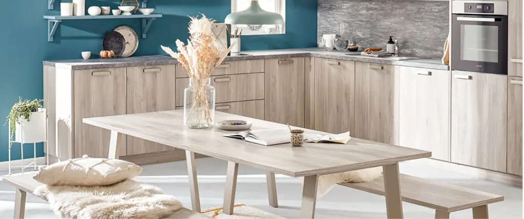 Helle Wohnküche mit blauen Fronten, Holzoptik und großem Esstisch. Skandinavisches Küchendesign mit offenen Regalen, moderner Beleuchtung und harmonischer Farbgestaltung für Familien und Genießer.